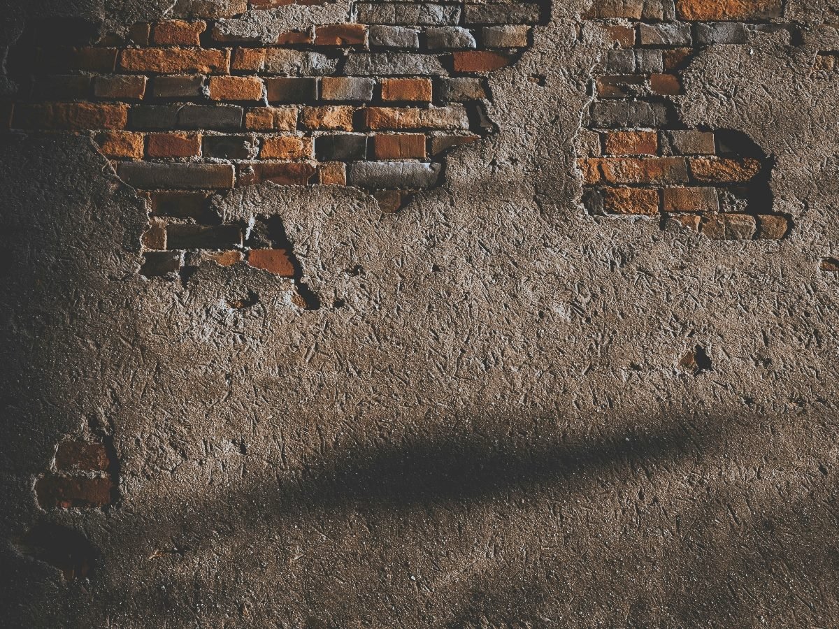 A brick wall with a grey concrete foundation covering most of it.