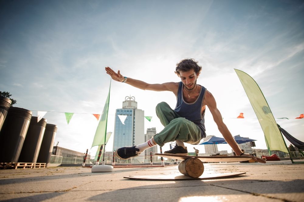 A young person balances on a board sitting on top of a ball with a cityscape in the background in piece about B2B marketing strategies.