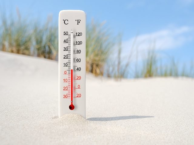  Hot summer day, with a Celsius and fahrenheit scale thermometer in the sand set at 6 degrees.