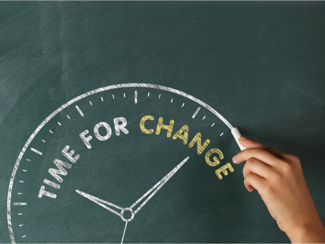 Handwriting on a chalkboard that says time for change, inside a hand-drawn clock