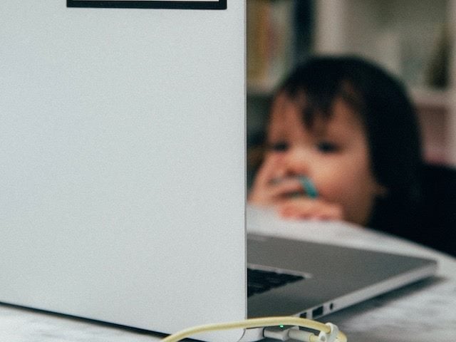 baby with a pacifier touching a laptop