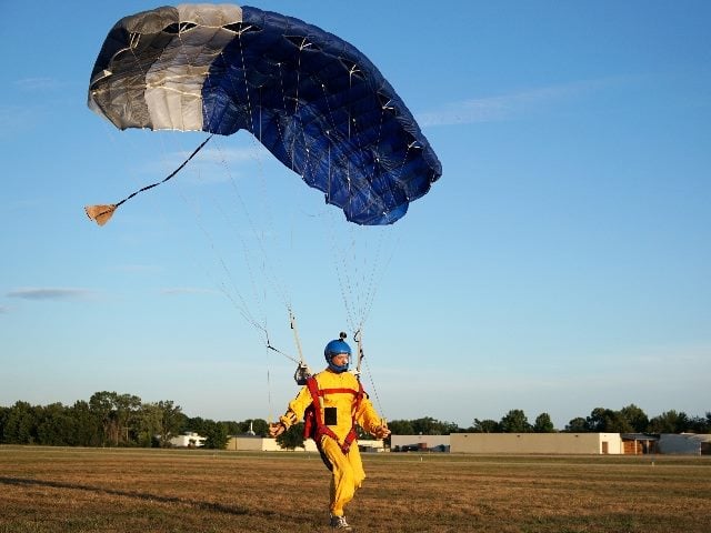  Landing of a parachuter against the background of forests and buildings.  