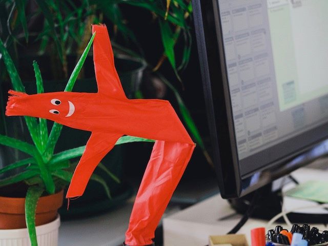 flailing toy figure next to an open laptop