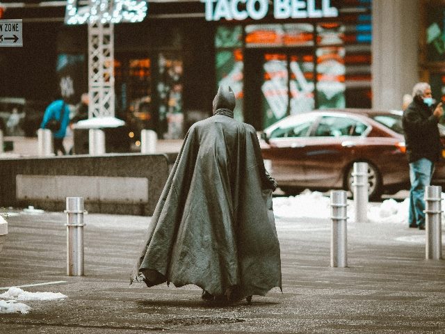 Shot from behind Batman walking toward a Taco Bell.