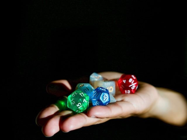person with a hand covered in Dungeons & Dragons dice
