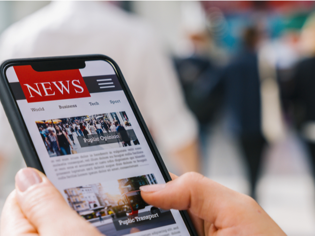Hands holding a smartphone with the word "News" on the screen.