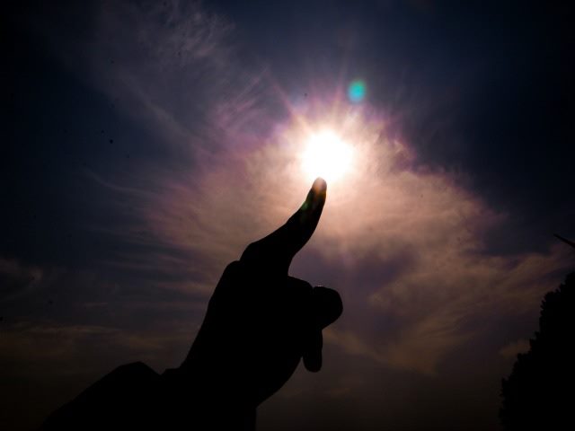 person's finger appearing to be touching the sun