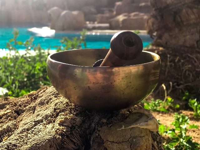 Tibetan singing bowl in the sun on the background of the water charged with solar energy. 