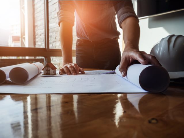 a man rolling out blueprints on a table.