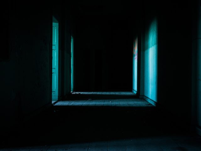 dark hallway with two doors open, allowing in a small amount of light