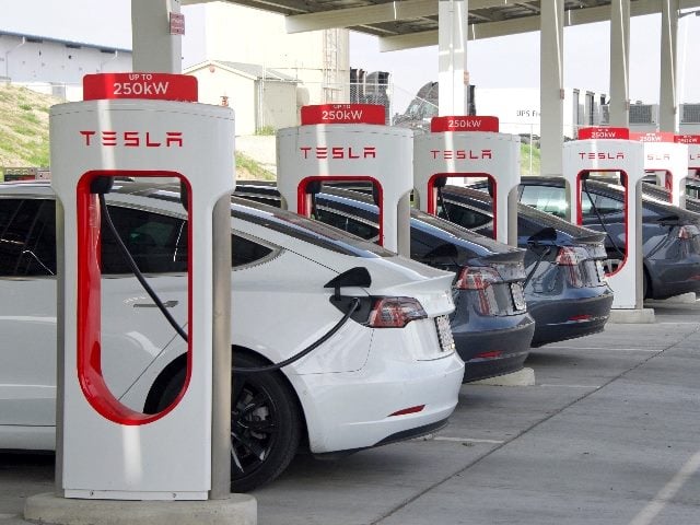 Many cars charging at a Tesla Supercharger station.  