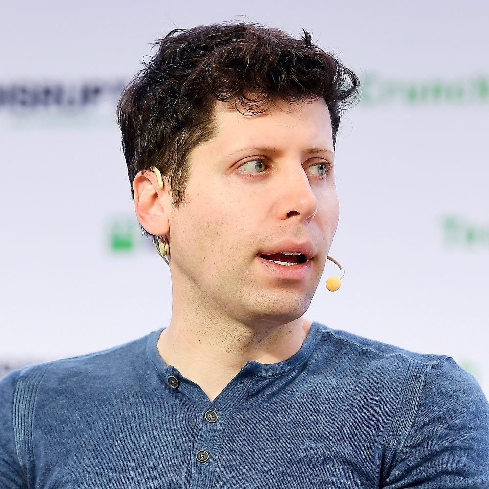 Sam Altman wears a casual blue shirt and a headset while speaking at TechCrunch Disrupt conference in piece about brand resonance.