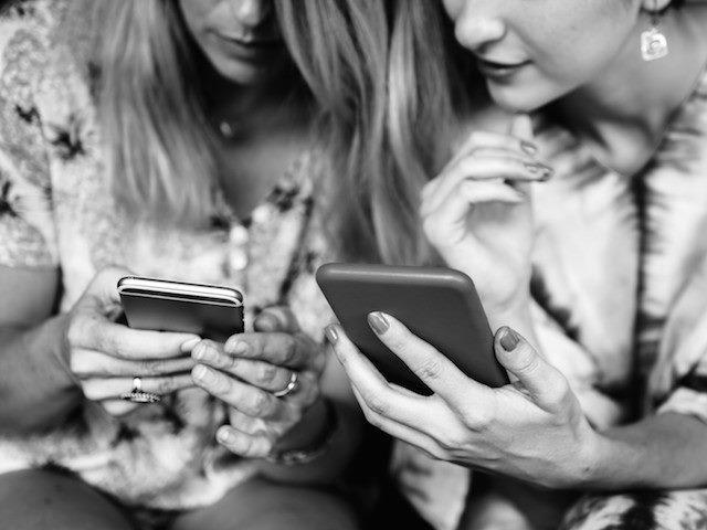 two women looking at their phones