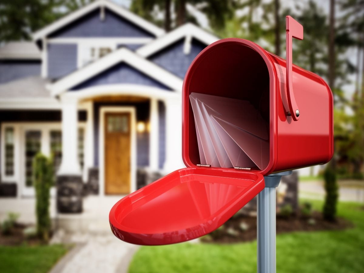 Open red mailbox filled with mail in front of a suburban home, symbolizing the inbox as a rich source of personal commerce and purchase data.