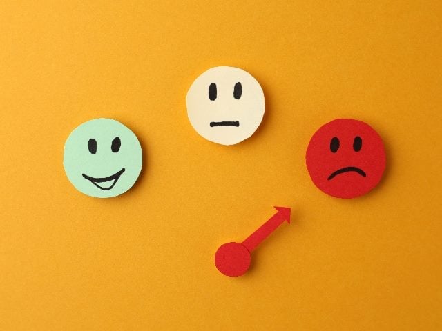 Three illustrations of faces representing different moods: green for happy, yellow for indifferent and red for sad, with a red arrow pointing to the sad face.