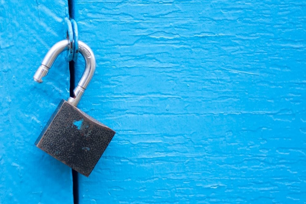 An open metal padlock hangs from a bright blue metal door, suggesting the potential opportunities Net Promoter Score can unlock.