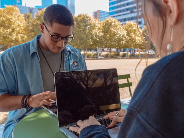 young couple working on laptops on a table outdoors