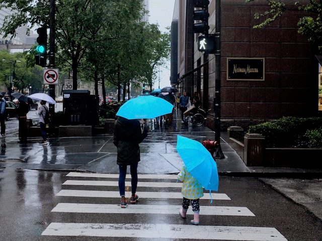 mother and daughter walking up the street  with matching umbrellas 