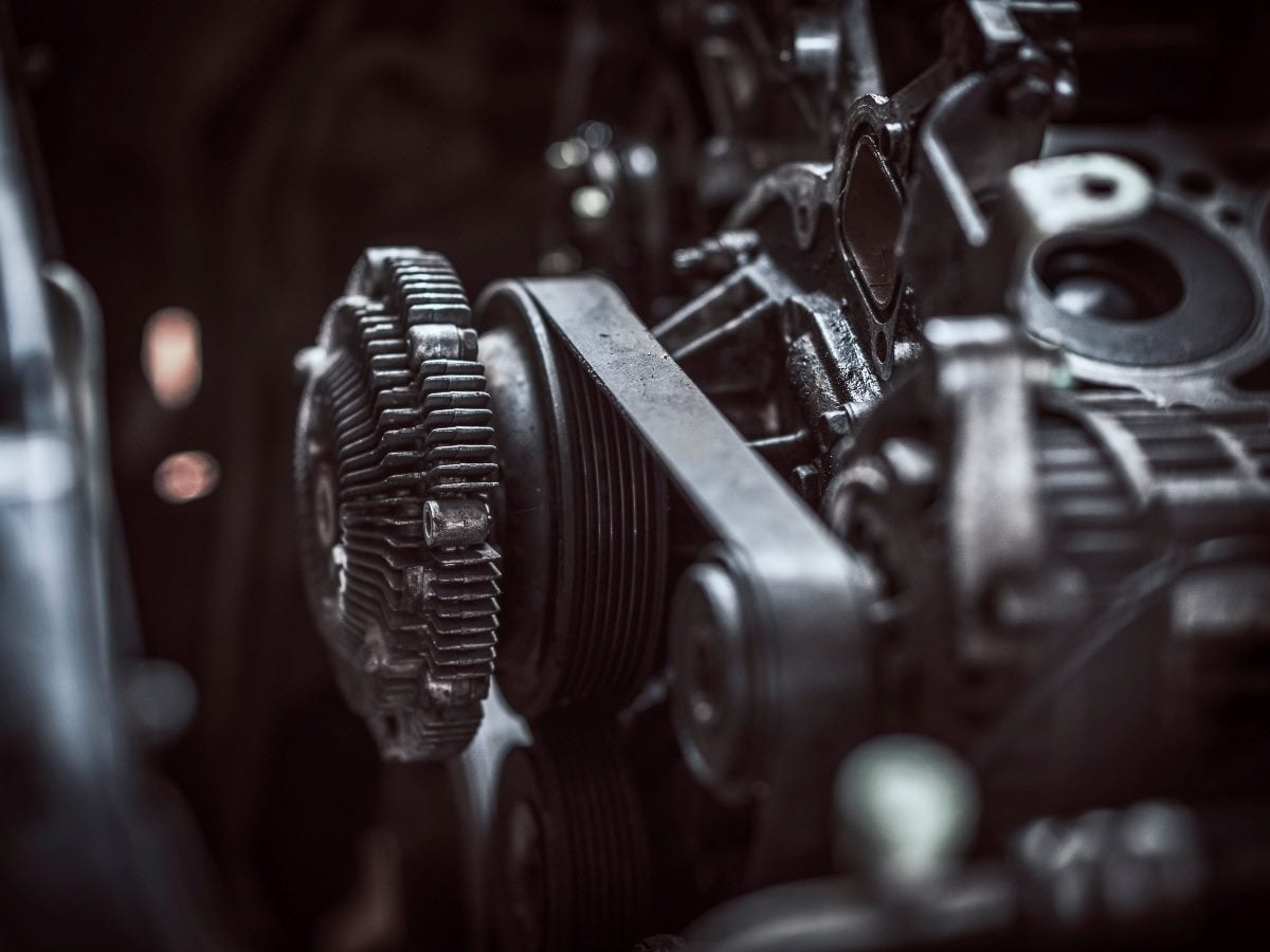A close-up view of mechanical engine components, including gears, belts and pulleys, symbolizing complex systems working together.