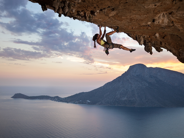 A woman scaling the a mountain with an island in the background