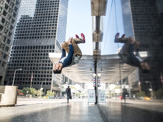 Man in mid-air doing a backflip on a city street.  