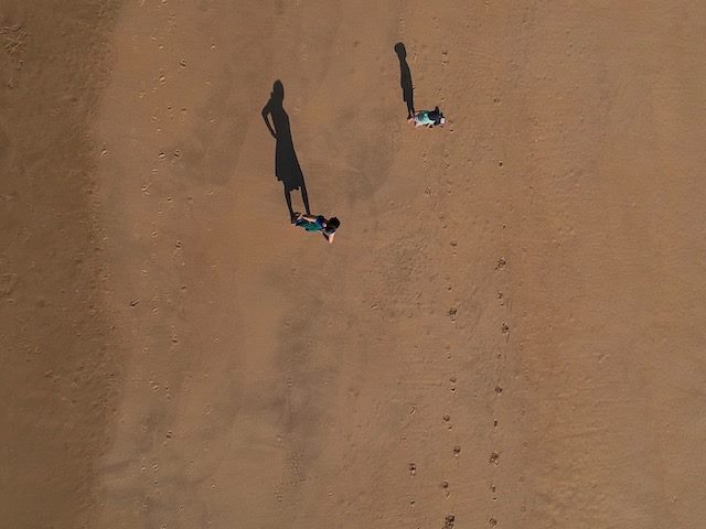 two people on the beach from above with  visible footprints  in the sand