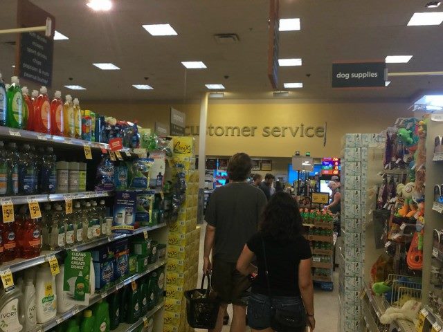 two customers in a store aisle walking toward a sign that says, "Customer Service."
