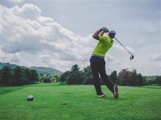 man in mid-swing on a golf course