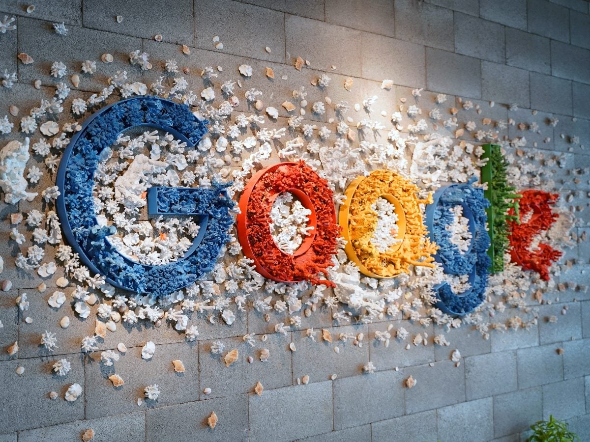 Google logo mounted on a stone wall, decorated with coral and seashell elements forming and surrounding the colorful letters.