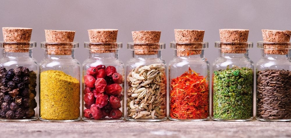 Clear bottles of spices, including nutmeg, fennel, turmeric, cumin, saffron and others, with thick corks in the top in piece about brand perception.