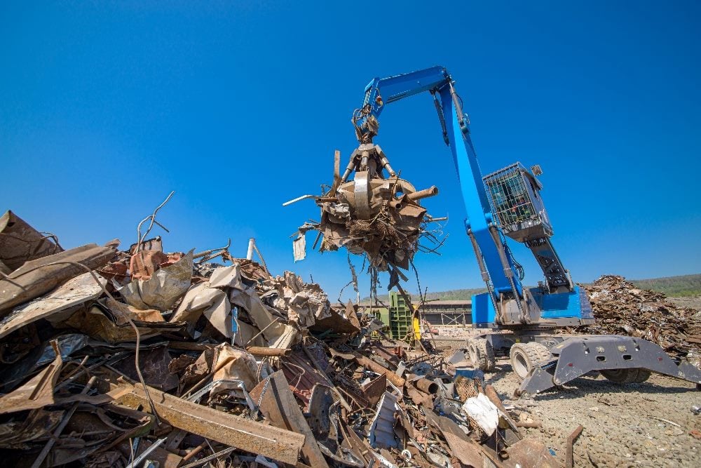 A bright blue industrial grabber used to load scrap metal in a junkyard in piece about the need to remove outdated content on websites.