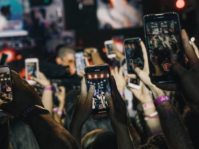 audience at a concert, all holding up their smartphones