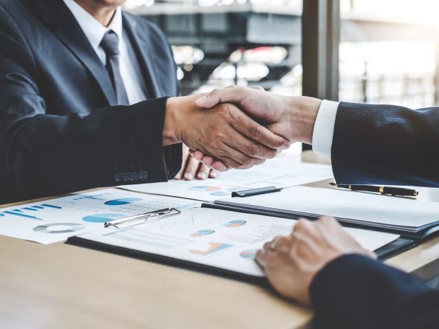 Two businessman shaking hands after signing a contract on a new platform