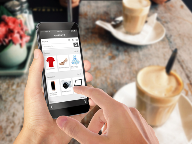 A man sitting at a restaurant table, while shopping on his smartphone - Mobile commerce concept
