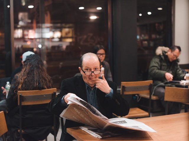 man licking finger to turn page of newspaper