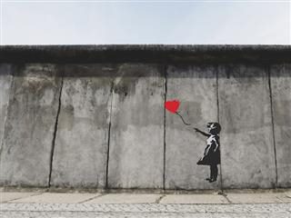 graffiti paste up of a girl letting go of a heart shaped balloon