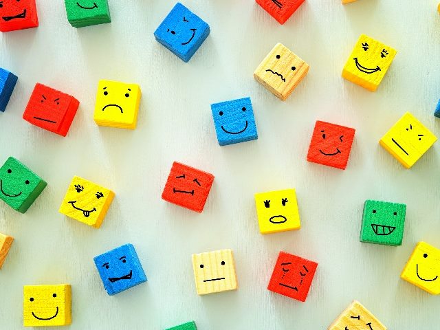 Colorful cubes illustration, showing several different emotional faces on the cubes. 