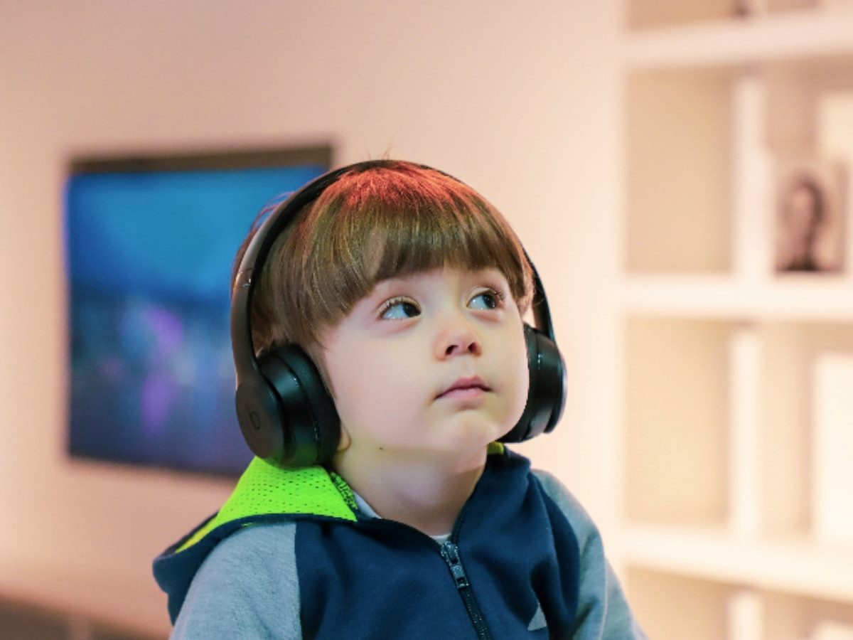 Young boy looking up as he listens to something on headphones.