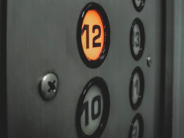 elevator panel, button lit up to go up to 12th floor
