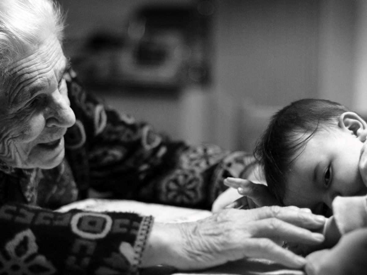 An elderly woman caring for a young baby.