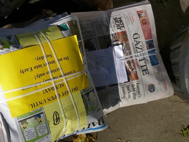 Two bundled up stacks of newspapers on the ground.