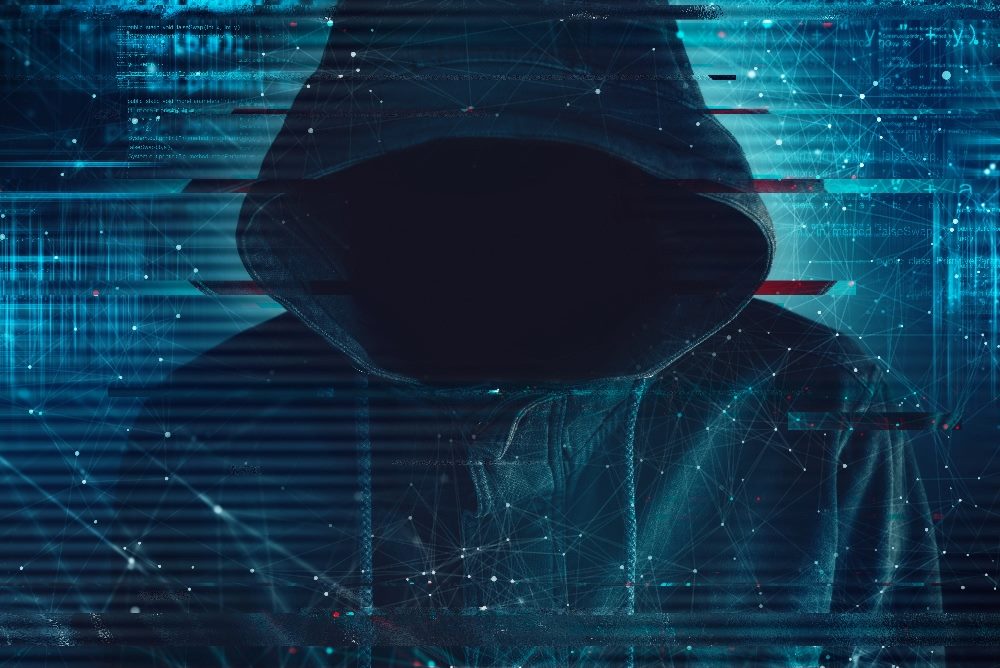 A faceless hacker wearing a dark hoodie stands in front of a blurred background of data points in blue light in piece about the Securities and Exchange Commission's new data breach rule.