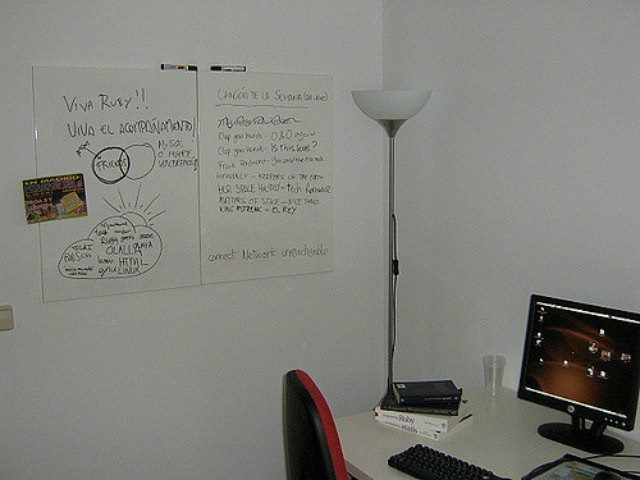 An empty office with a computer and sign taped to the wall.