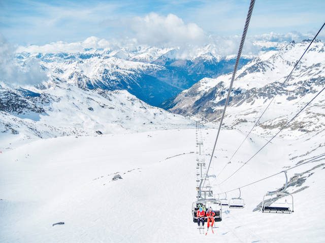 people riding a ski lift on a snow covered mountain