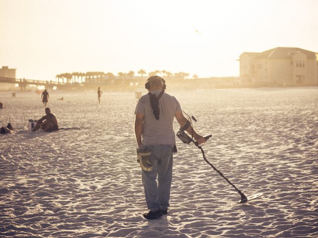 man with geiger counter walking the beach