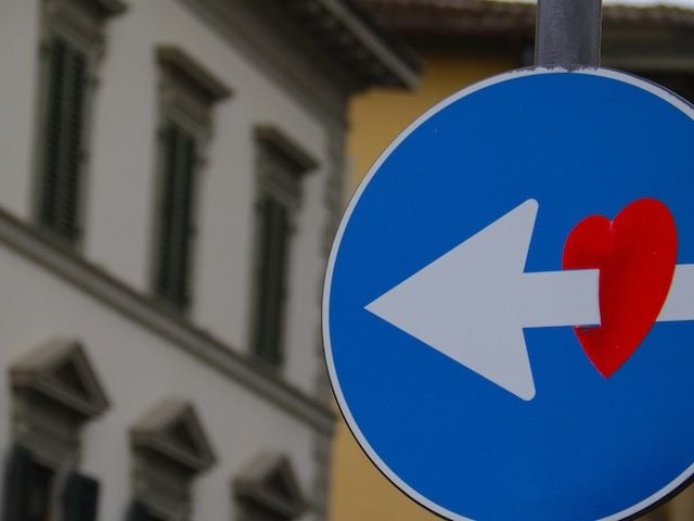 street sign with arrow piercing a heart