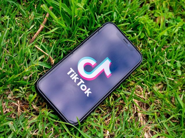 phone with TikTok logo on screen lying in green grass backgroun