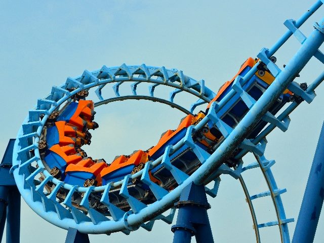 A bright blue roller coaster with red and dark blue cars is filled with thrill seekers in piece about Google Gemini's Image Recognition rollback. 