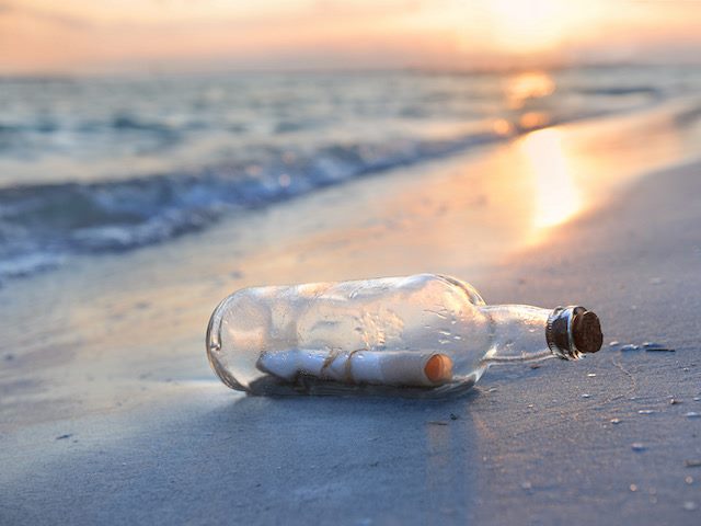 message in a bottle on the beach at sunset
