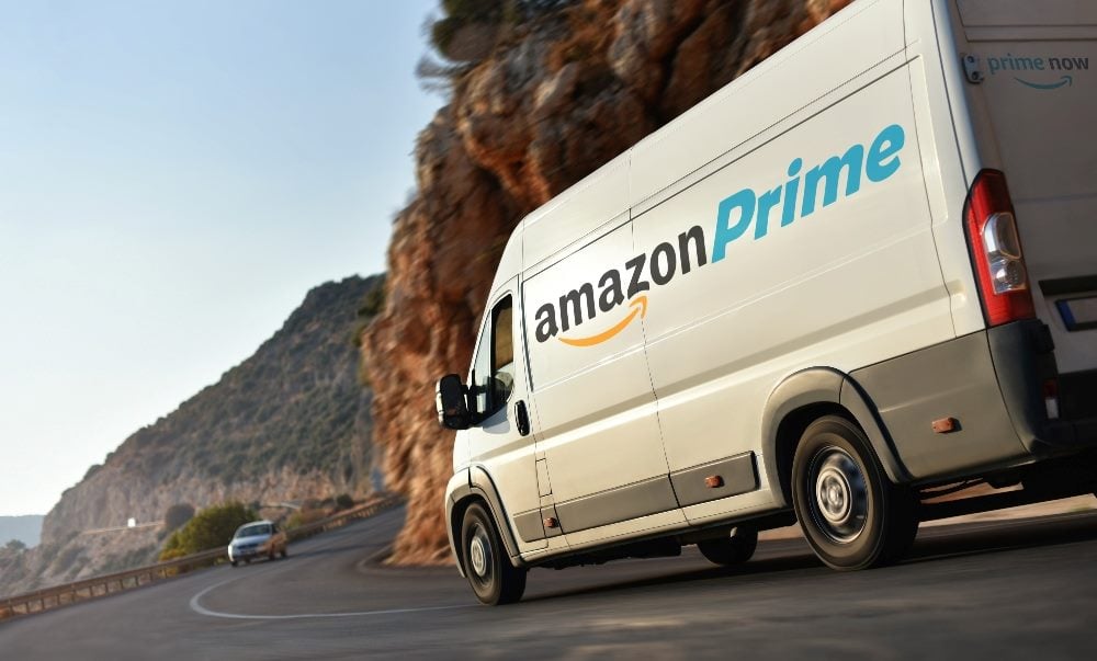 A white Amazon truck drives around a curve on coastal road in piece about canceling Amazon Prime.